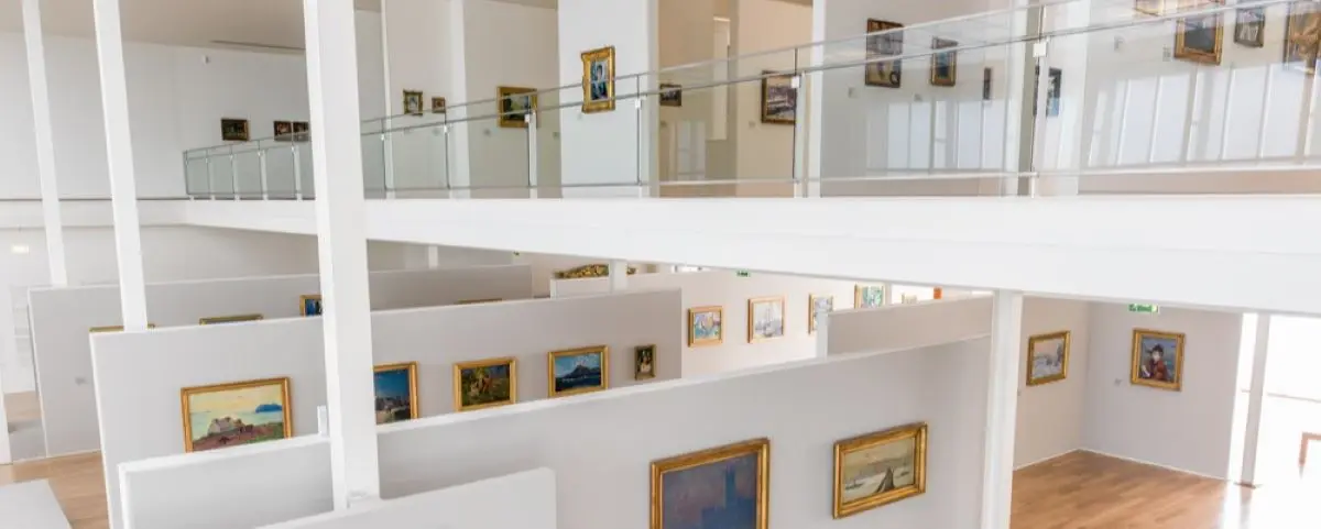 An interior view of the Andre Malraux Modern Art Museum in Le Havre, showcasing multiple levels with walls adorned with framed paintings.