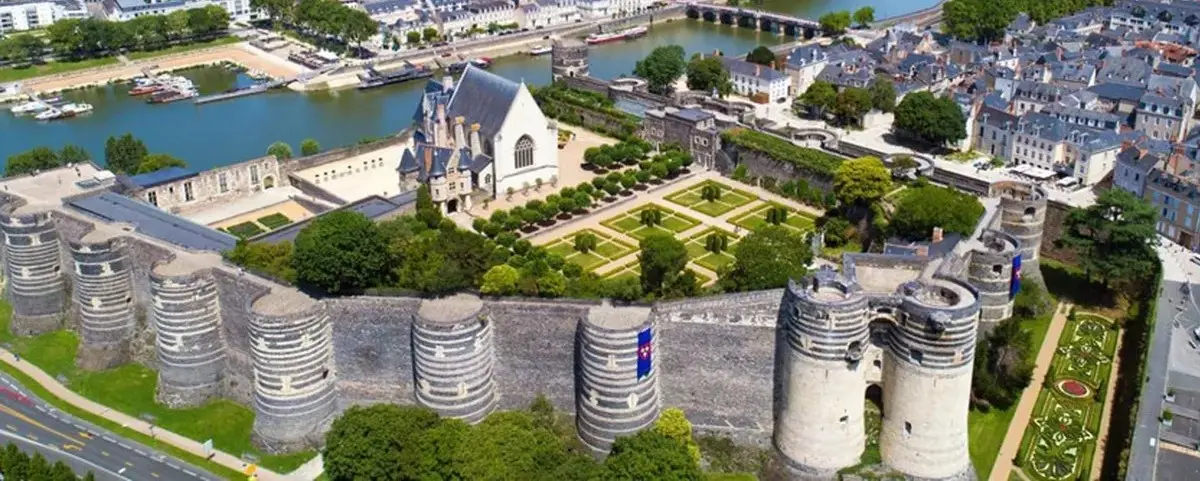 Aerial view of Angers Castle, showcasing its medieval stone towers, manicured gardens, and the surrounding townscape near the river.