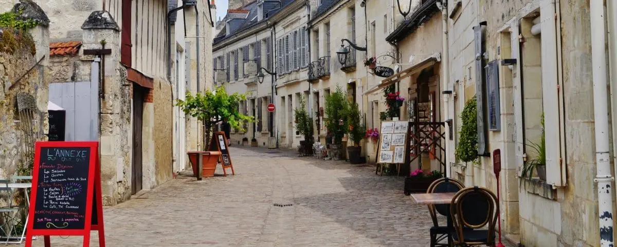 Charming cobblestone street in Azay-le-Rideau lined with historic buildings, quaint shops, and outdoor seating, creating a picturesque village atmosphere.