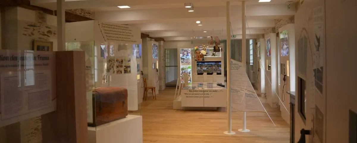 Museum exhibit area with informational displays, historical artifacts, and educational panels, housed in a well-lit room with wooden flooring.
