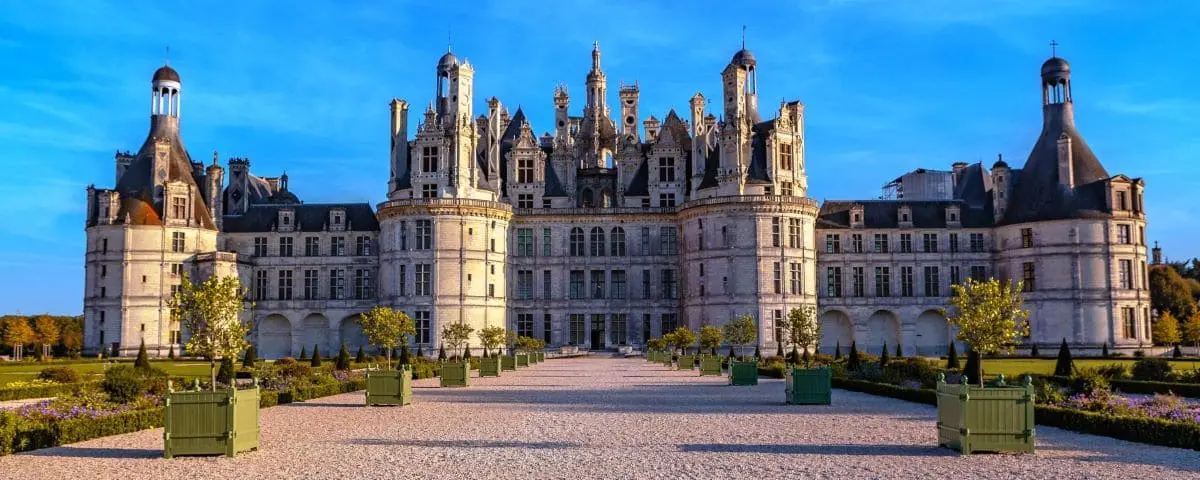 Grand view of Chambord Castle with its elaborate Renaissance architecture, symmetrical gardens, and clear blue sky.