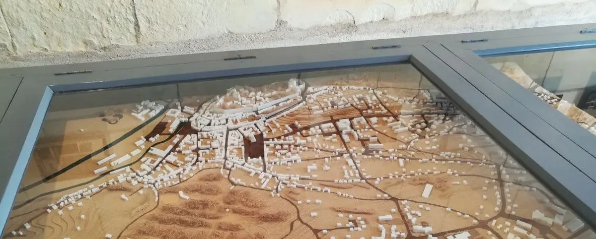 A scale model of a historic town displayed under glass at the Chancellerie Museum in Loches. The model features intricate details of buildings, streets, and surrounding landscape.