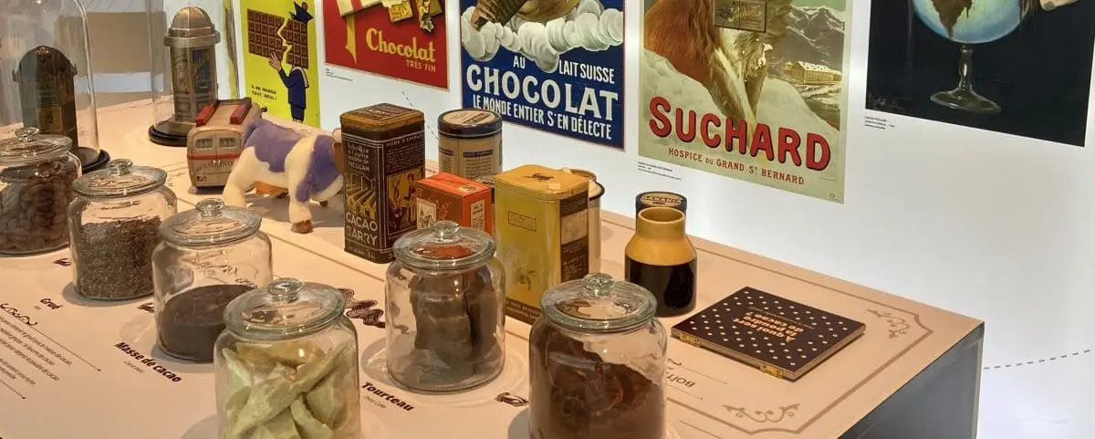 Exhibit at the chocolate museum in Fécamp featuring vintage chocolate advertisements and various jars and containers of cocoa products.