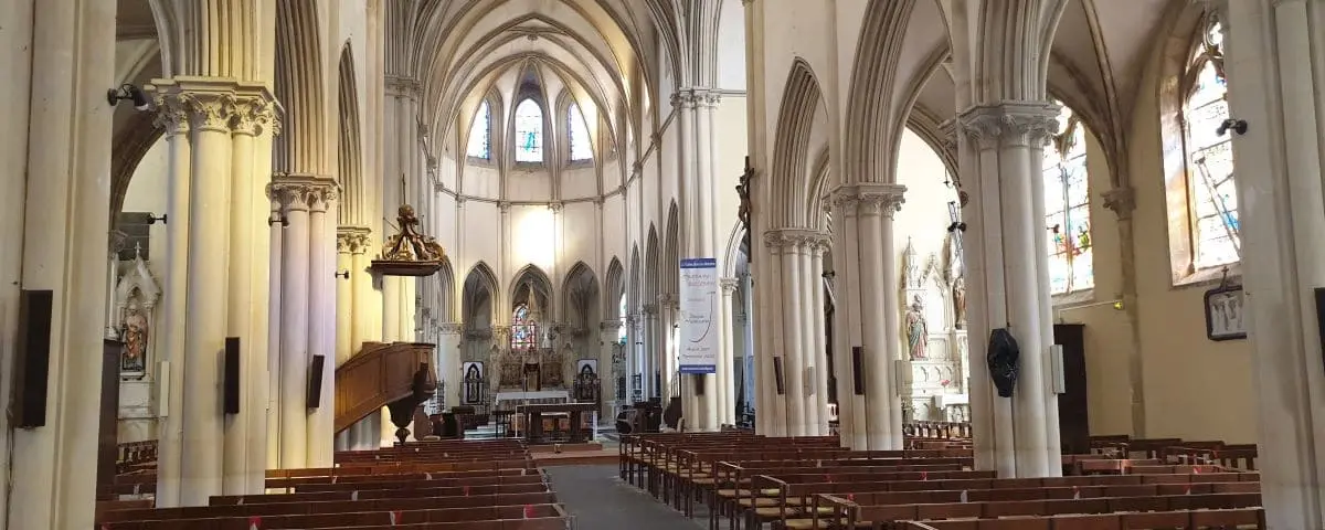 Interior view of the Church of Saint Vaast, showcasing its gothic architecture with tall columns and stained glass windows.