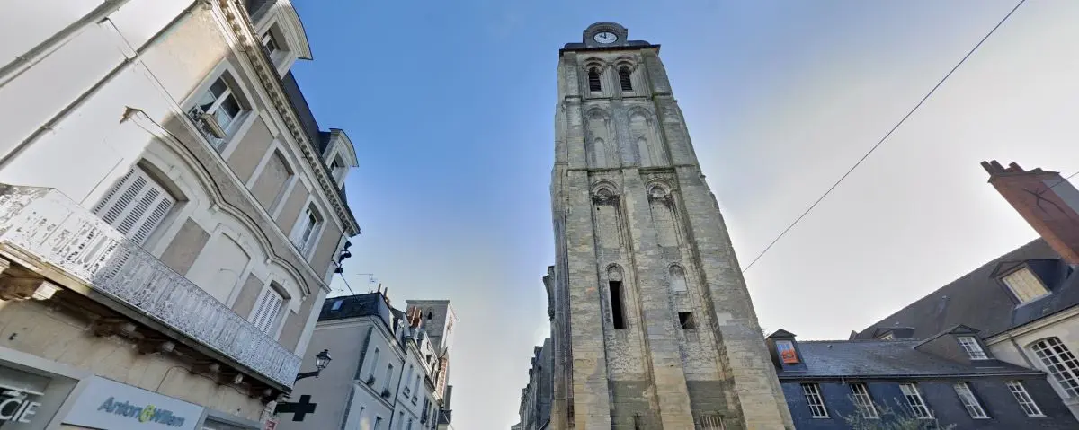 An exterior view of a historic clock tower in Tours, France, situated in a European city, with surrounding old-style buildings and a clear sky above.