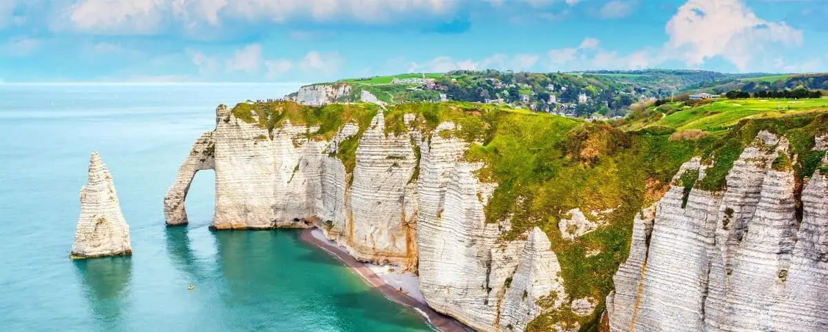 Scenic view of the white chalk cliffs of Etretat, with natural arches and blue waters of the English Channel.