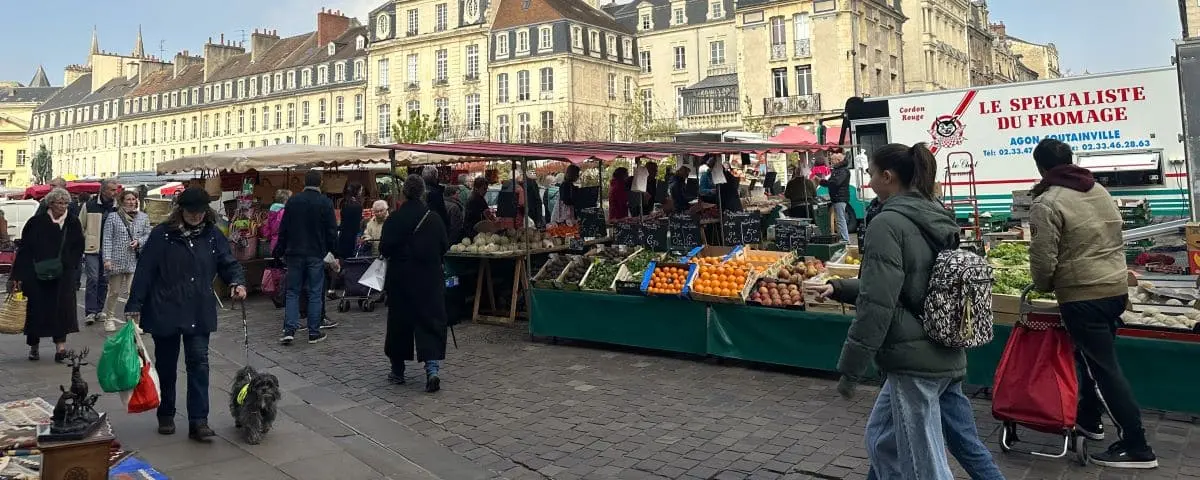 A bustling outdoor food market with stalls selling fresh produce, cheese, and other goods. Shoppers browse the vibrant market, enjoying the lively atmosphere.