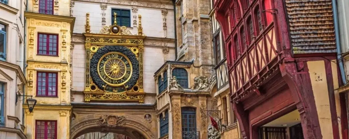 The iconic Gros-Horloge in Rouen, a large and ornate astronomical clock set within a beautifully decorated archway, surrounded by historic half-timbered buildings.