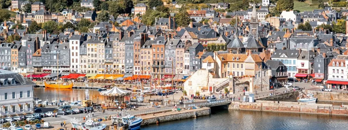 Charming port of Honfleur town, with colorful buildings lining the waterfront and boats docked in the harbor.