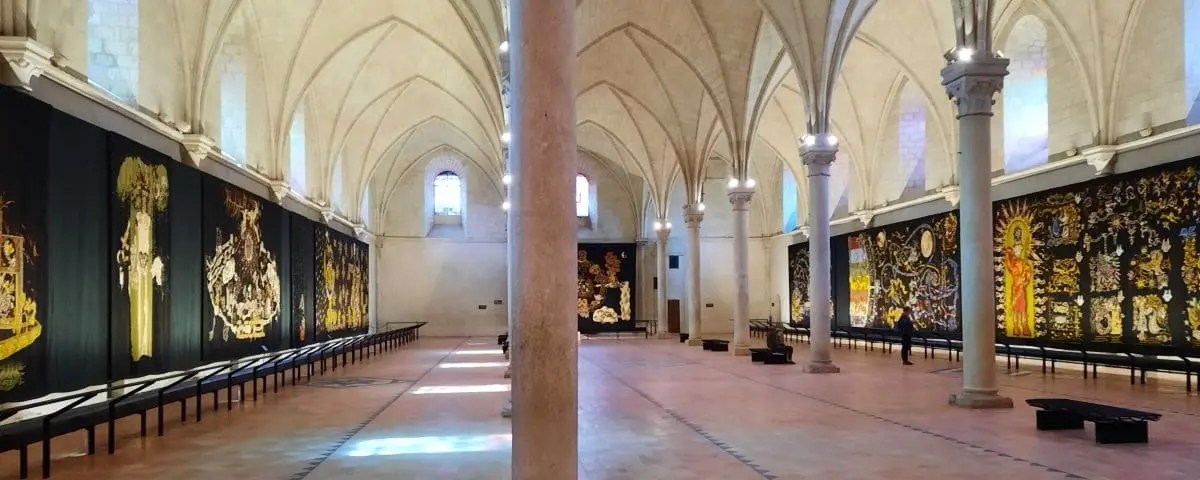 Interior of the Jean Lurçat Museum displaying large tapestries with intricate designs and vibrant colors, set against the Gothic architecture of the building.