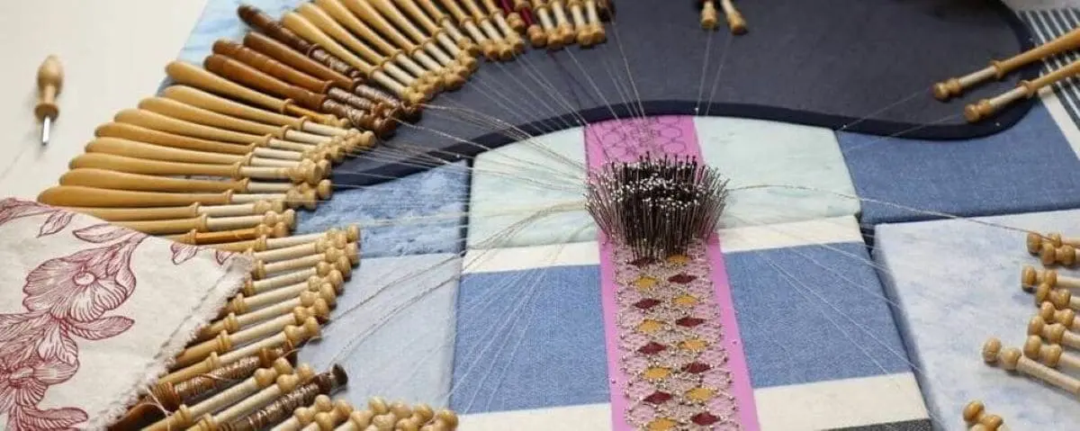 A detailed close-up of lace-making tools and materials arranged in a workshop, showcasing the intricate craft of lace-making.