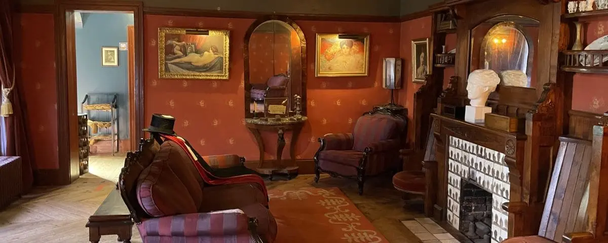 Cozy interior of Le Clos Lupin, Maurice Leblanc's house in Etretat, decorated with vintage furniture, paintings, and a warm fireplace.