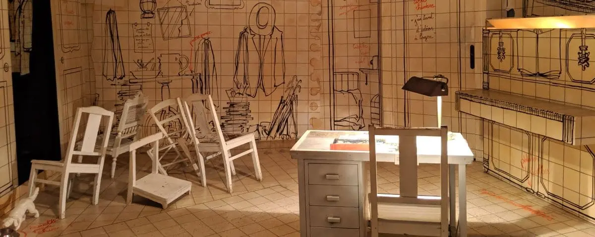An artistic exhibit within Maisons Satie, showing a room decorated with whimsical, hand-drawn furniture and objects on the walls. The room is designed to evoke a creative and imaginative environment.