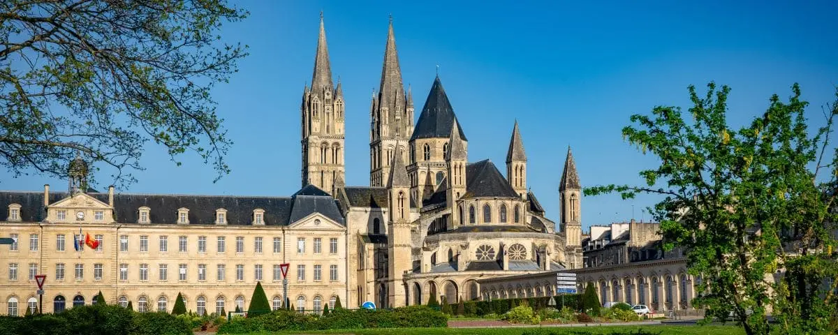 The majestic Men's Abbey with its towering spires and historic architecture. The well-kept grounds and clear sky emphasize the grandeur of the abbey.
