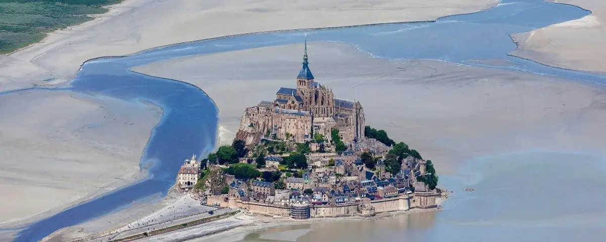 Aerial view of Mont Saint-Michel, a medieval abbey perched on a rocky island surrounded by tidal waters.