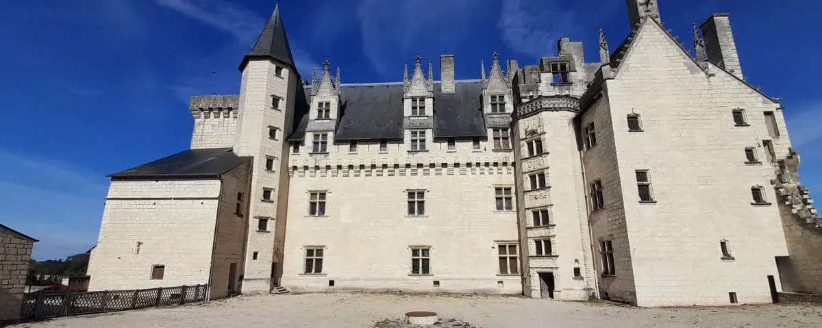 The impressive Montsoreau Castle with its tall towers and stone walls, set against a bright blue sky.