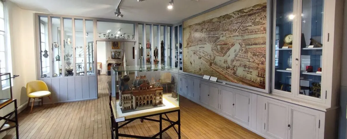 An interior view of the Museum Hotel Dubocage in Le Havre, displaying historical artifacts and a large map on the wall.