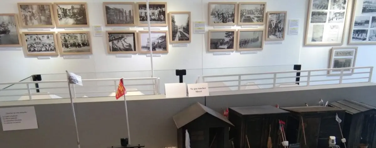Interior of the Museum of Heritage in Etretat, displaying historical photographs and artifacts, with a model of an old railway station in the foreground.