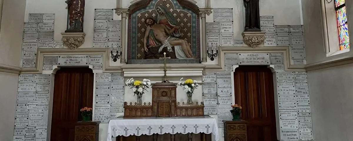 The altar of Notre Dame de Pitié chapel in Deauville, featuring religious statues and flower arrangements.