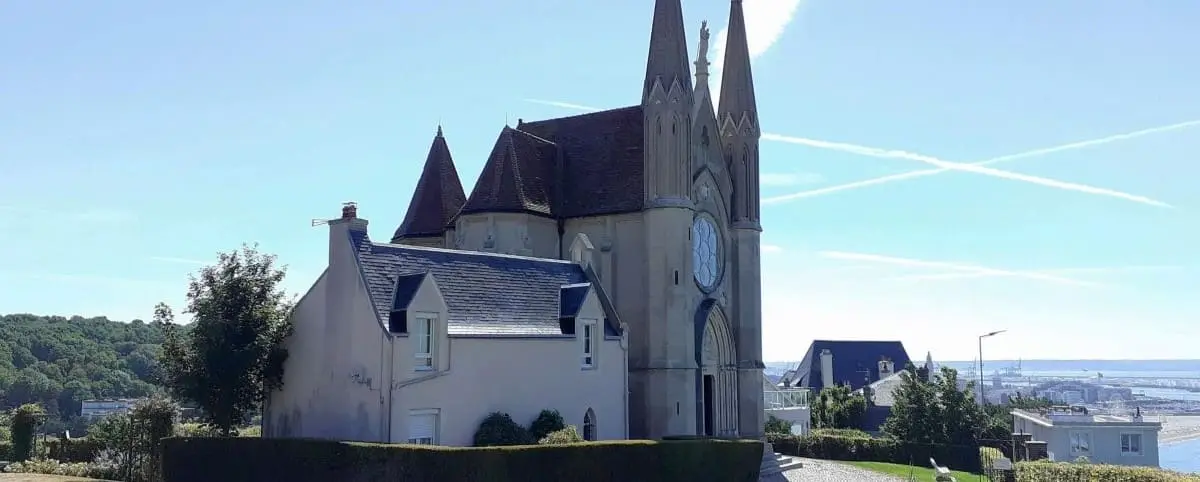 The Notre Dame des Flots Chapel in Le Havre, with its distinctive pointed towers and picturesque setting against a clear sky.