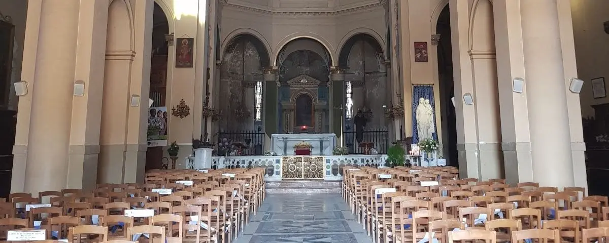 The interior of Notre-Dame-des-Victoires Church in Trouville, featuring rows of wooden chairs facing an ornate altar adorned with religious icons and decor.