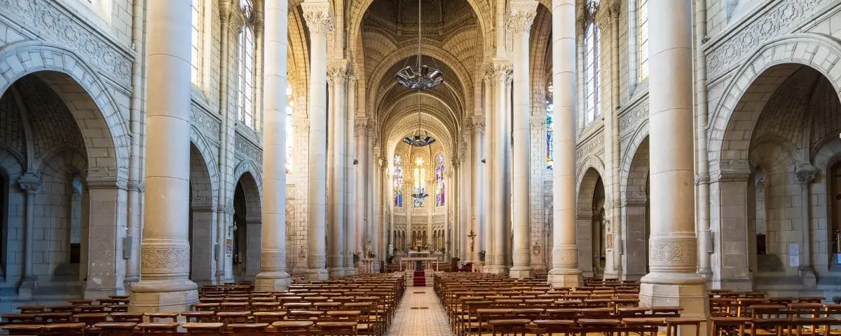Interior of Notre Dame des Victoires Church, highlighting its grand arched ceilings, ornate columns, and rows of wooden pews leading to the altar.