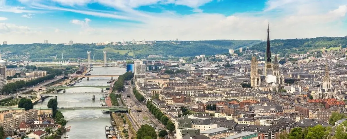 Panoramic view of Rouen city, showcasing the Rouen Cathedral and the Seine River winding through the urban landscape.