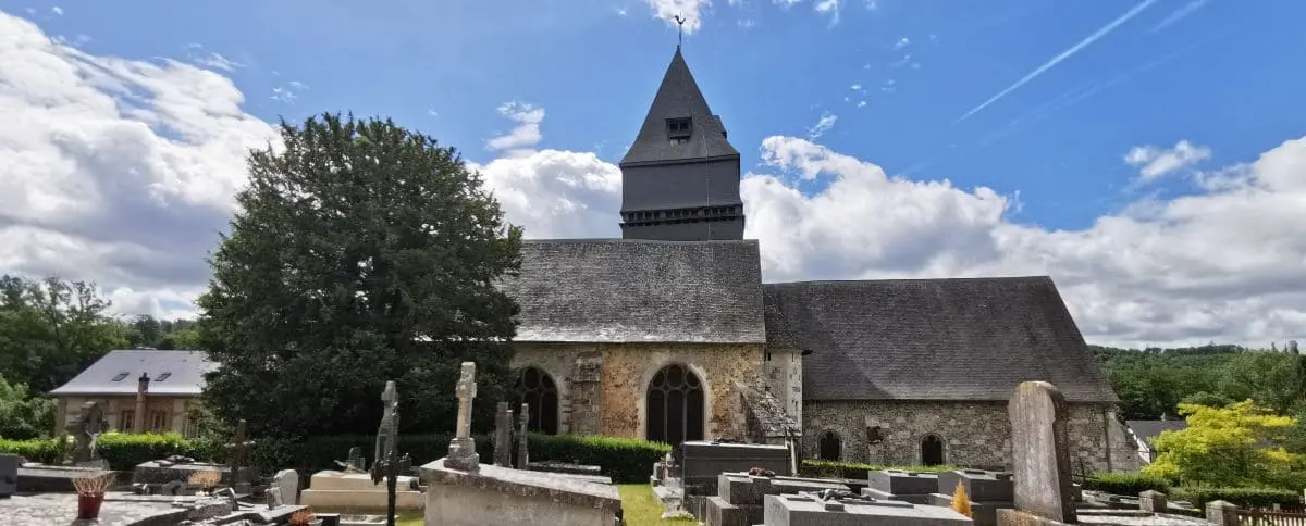 Exterior view of Saint-Denis Church with its distinctive dark wooden steeple, stone walls, and surrounding graveyard, under a bright blue sky with scattered clouds.