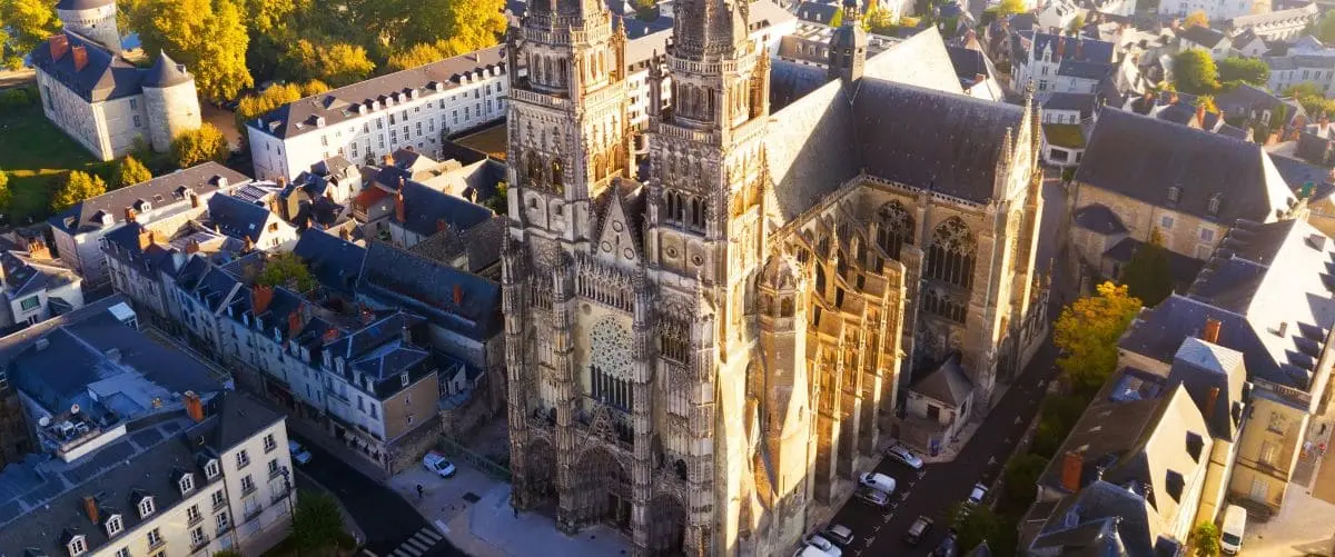 Aerial view of the grand Saint Gatien Cathedral in Tours, France, with its towering Gothic spires, surrounded by the cityscape of Tours.