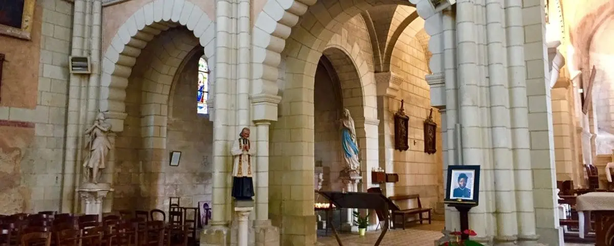 Interior view of Saint Jean Baptiste Church in Langeais, featuring stone arches, religious statues, and a serene atmosphere inside the historic church.