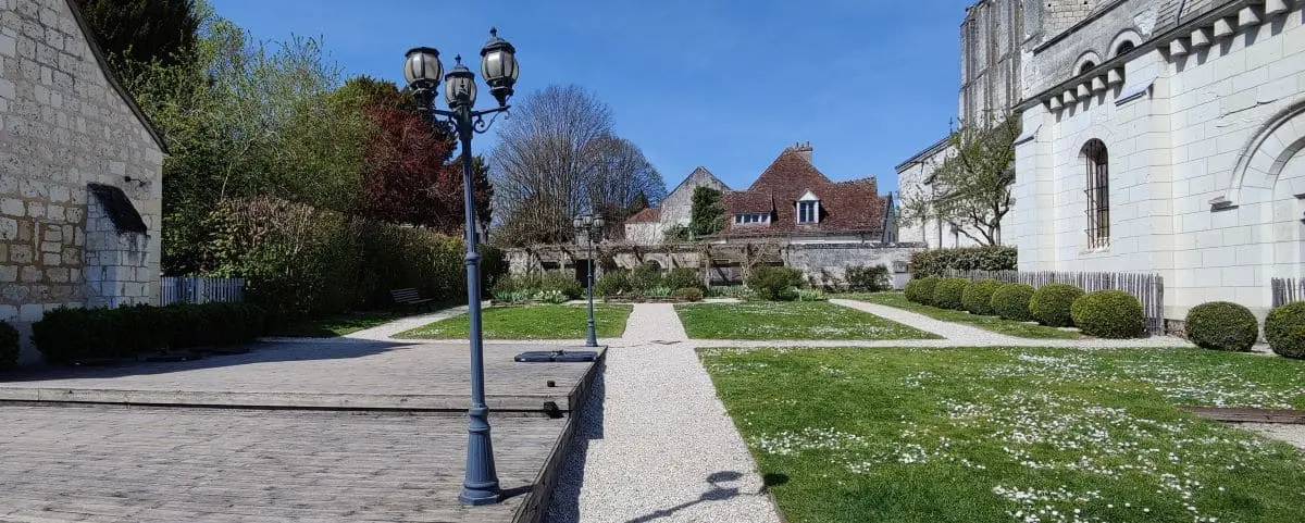 A neatly maintained garden in Loches with pathways, greenery, and a few lamp posts. The garden is surrounded by historic stone buildings.