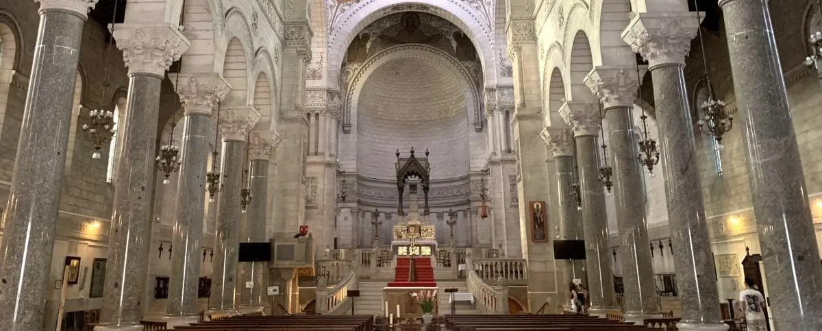 The majestic interior of Saint Martin Basilica in Tours, France, showcasing grand columns, intricate stone carvings, and a central altar under a domed ceiling.