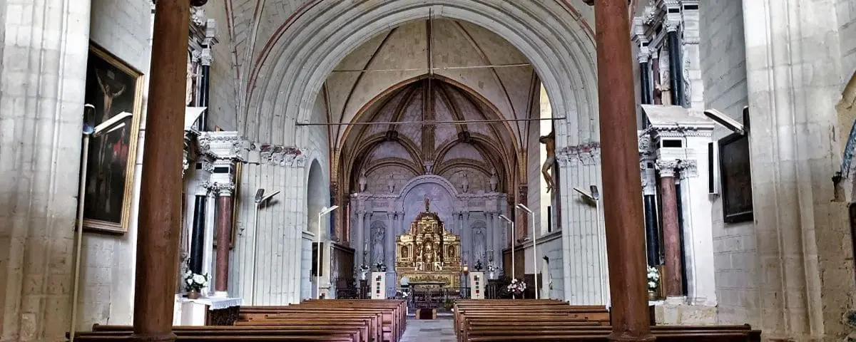 The interior of Saint-Michel Church in Fontevraud, showcasing an ornate altar, wooden pews, and vaulted ceilings with arches.