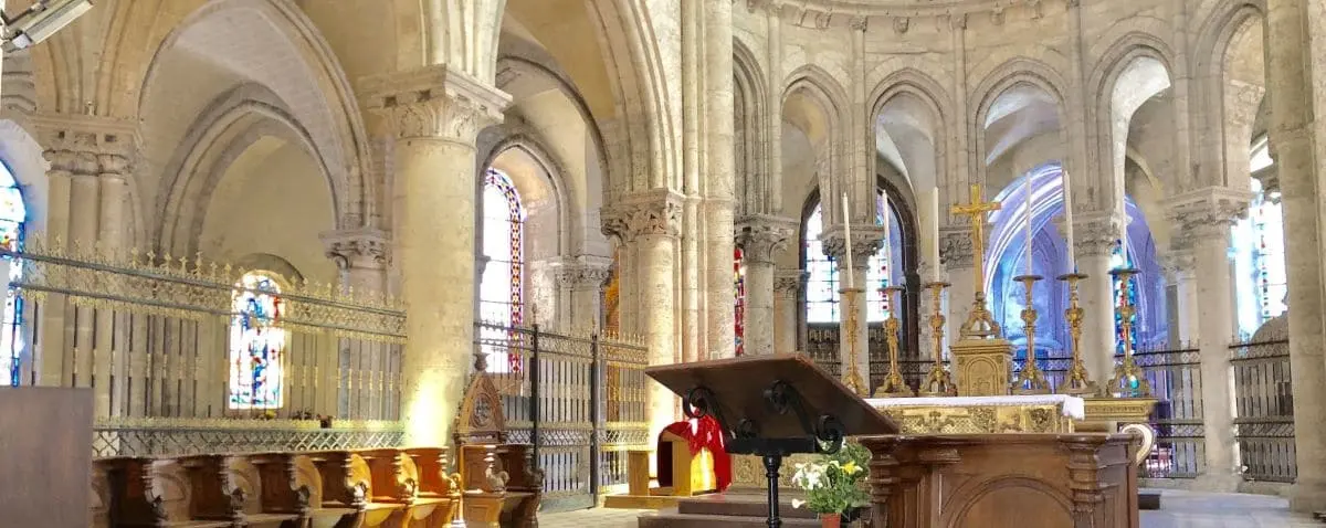The interior of Saint Nicolas Church with its ornate altar, gothic arches, and beautiful stained glass windows.