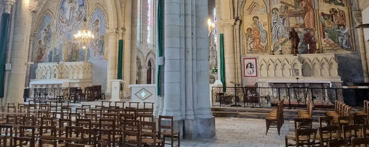 Interior view of Saint Nicolas Church in Saumur, showcasing ornate religious murals, wooden chairs, and a beautifully decorated altar.