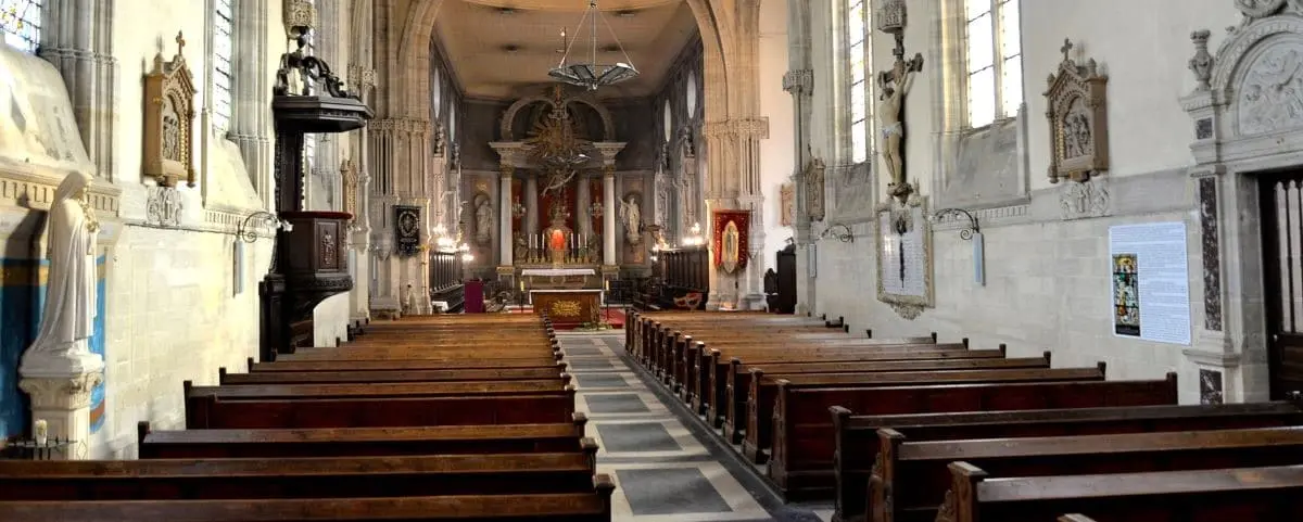 The interior of Saint Patrice Church with rows of wooden pews, a decorated altar, and ornate architectural details on the walls.