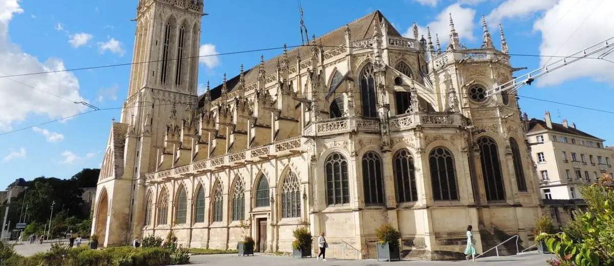 The exterior of Saint Pierre Church in Caen, highlighting its detailed gothic facade and towering spire. The clear sky and surrounding buildings add to the church's grandeur.