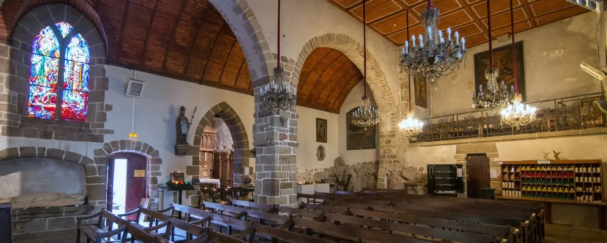 The interior of Saint-Pierre Church at Mont Saint-Michel, featuring stone arches, wooden pews, and stained glass windows.