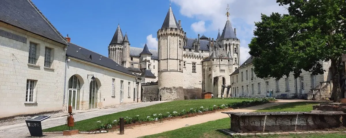 The picturesque Saumur Castle with its pointed towers and stone walls, surrounded by well-maintained gardens and pathways.