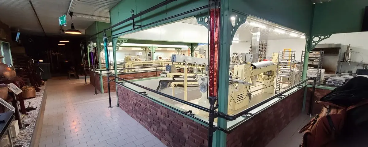 An interior view of a sweet factory with vintage machinery and production lines. The room is brightly lit and features a mix of modern and old-fashioned equipment used in confectionery production.