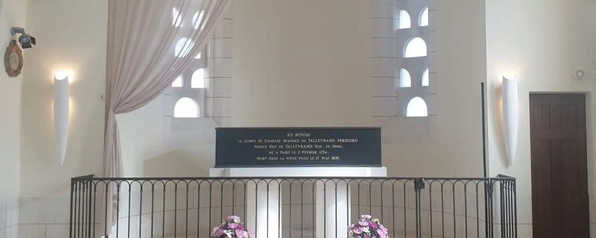 The serene interior of the Talleyrand Tomb Chapel in Valençay, displaying a simple, elegant tomb with an inscription, framed by light streaming through small windows.