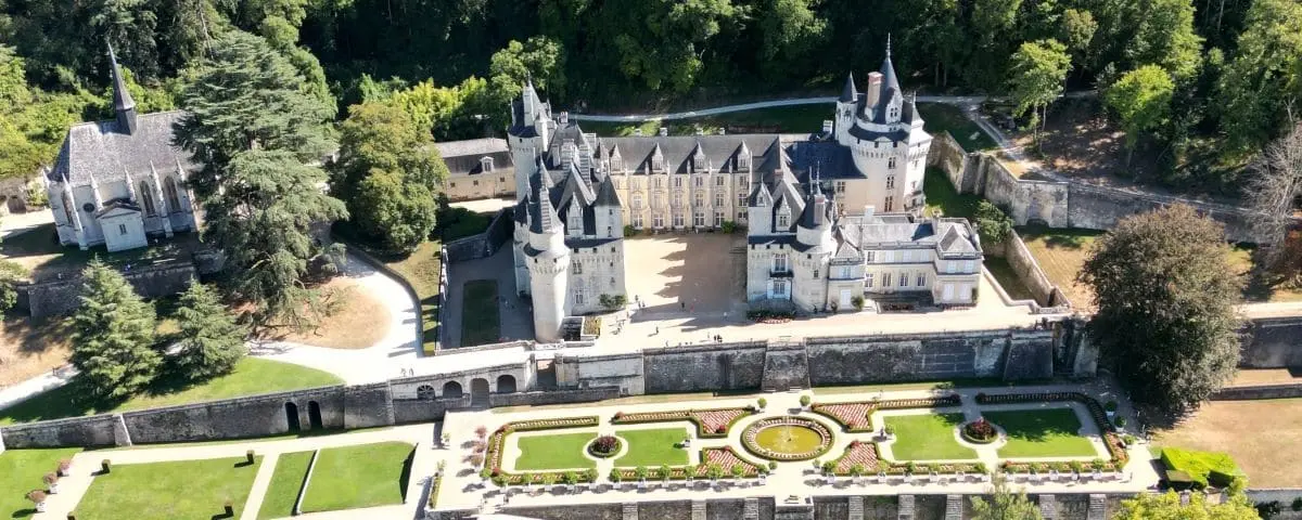 A fairy-tale-like castle with numerous pointed towers and intricate architectural details, set amidst a verdant landscape.