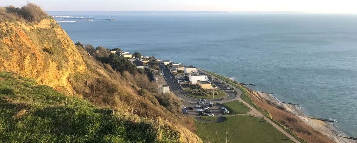 A coastal view from Cap de la Heve in Le Havre, showing a cliffside overlooking the sea and a small community below.