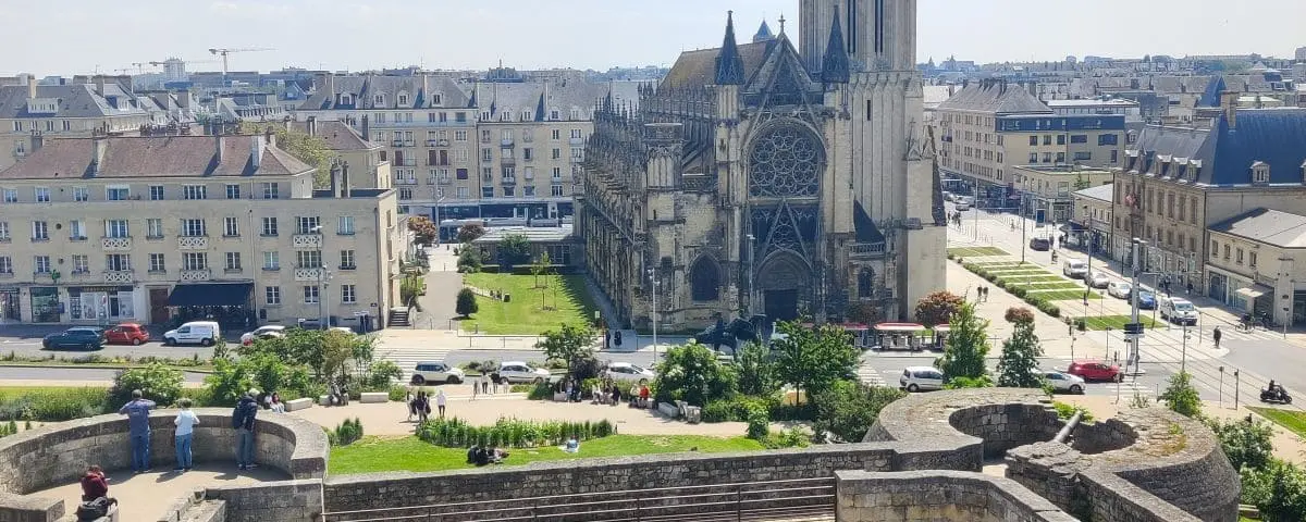 A view overlooking Saint Pierre Church and the surrounding cityscape. The green lawns and historic architecture provide a picturesque scene.